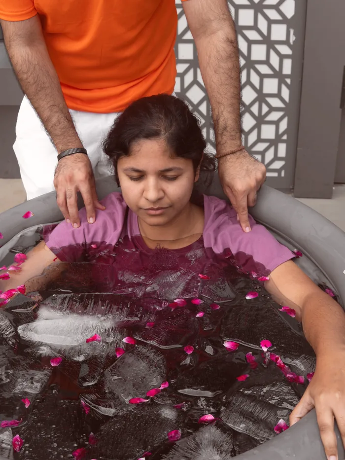 A guest steadied by a facilitator during a guided cold immersion