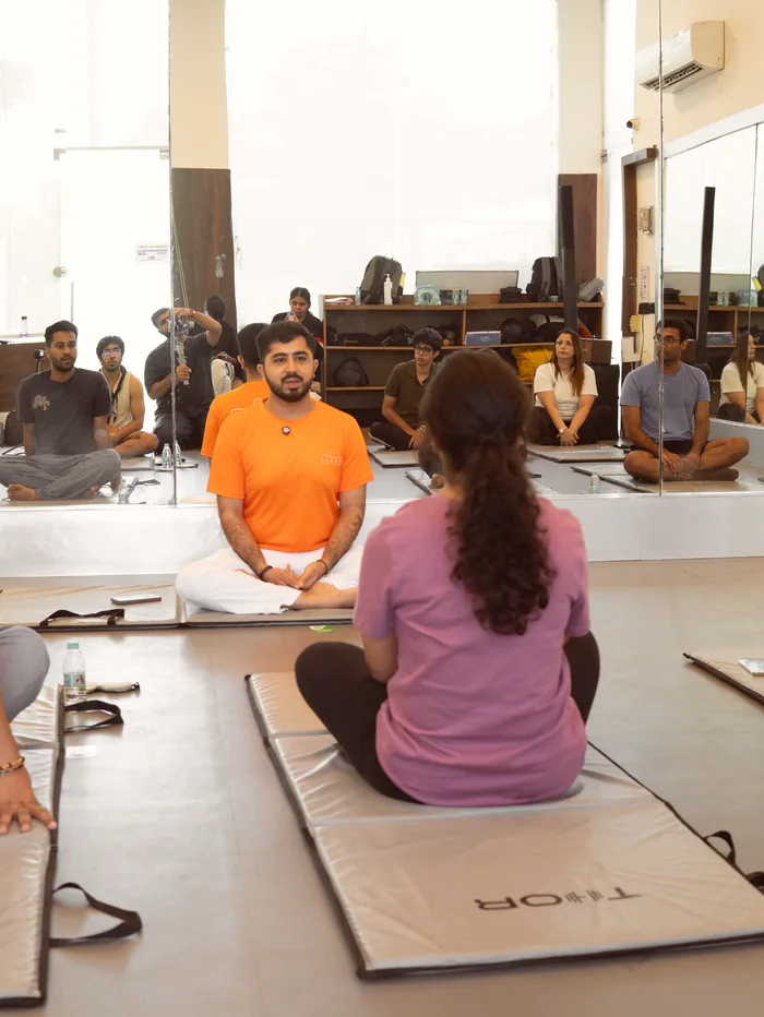 The teacher sitting opposite a participant, talking her through a round