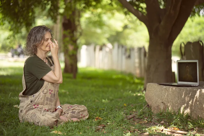 A woman sitting in alternate-nostril breathing under a mango tree