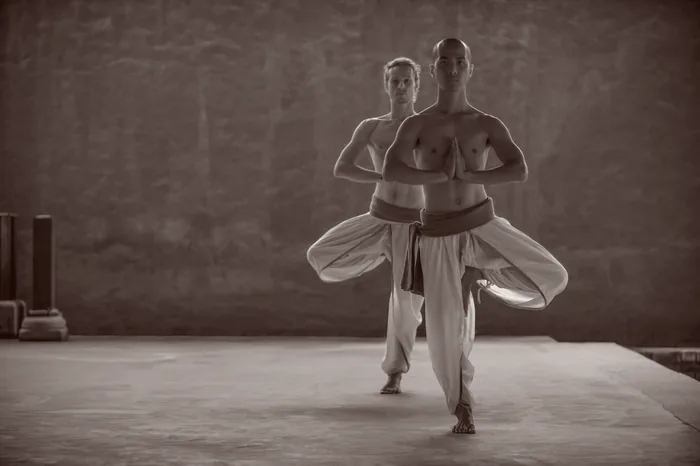 A long-exposure frame of a practitioner turning through tree pose