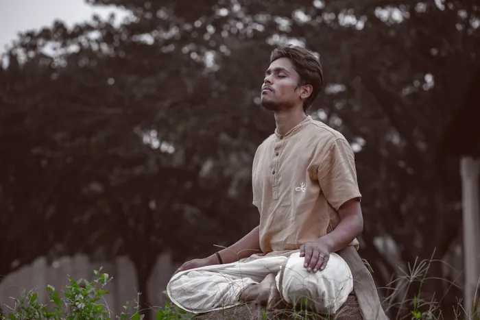 A practitioner seated in meditation with green behind him
