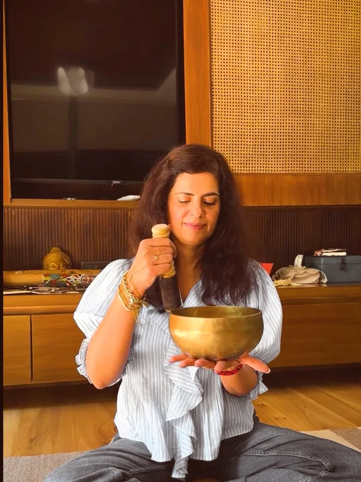 A sound practitioner striking a singing bowl held in her palm