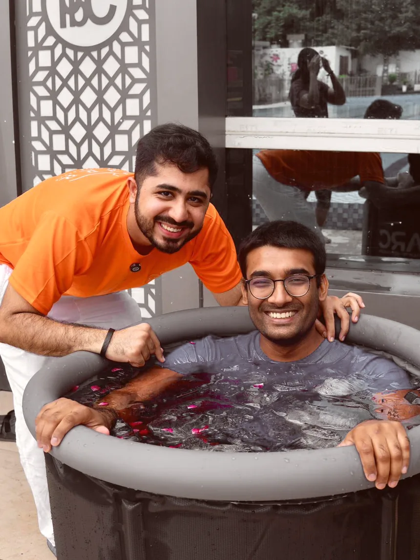A guest grinning through a guided cold immersion strewn with rose petals