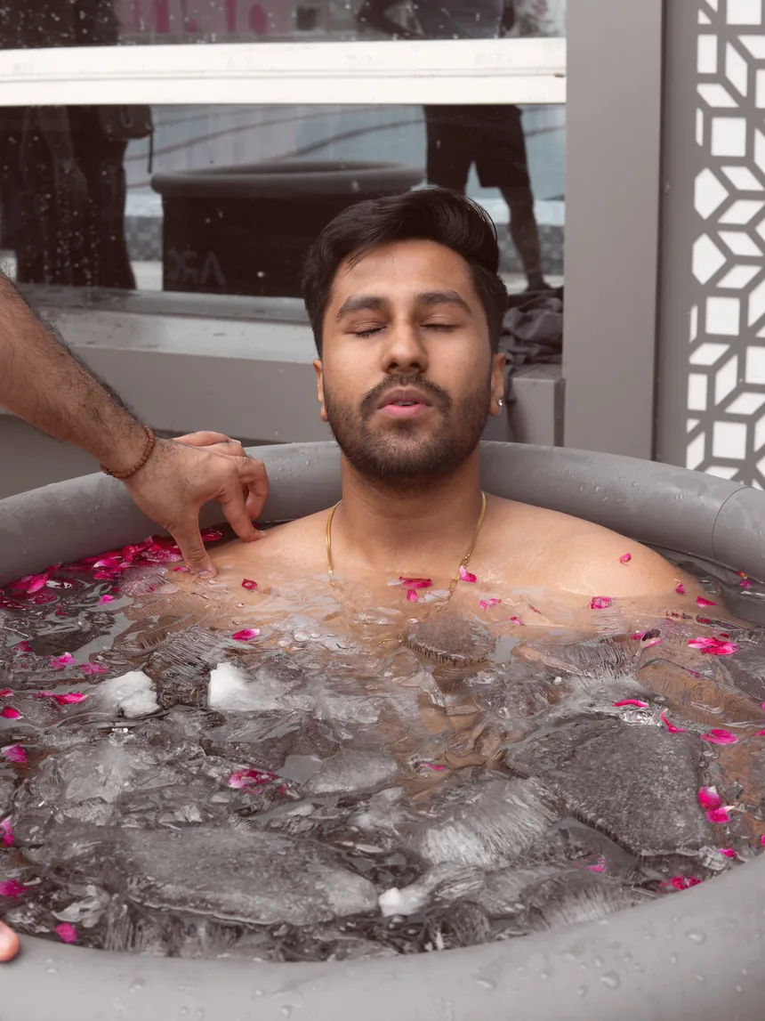 A guest in a guided cold immersion with rose petals on the water
