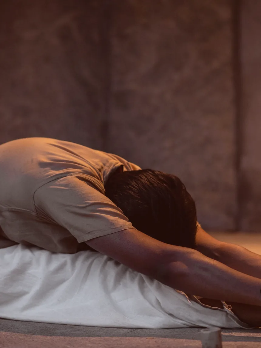 A practitioner folded forward over her legs, resting