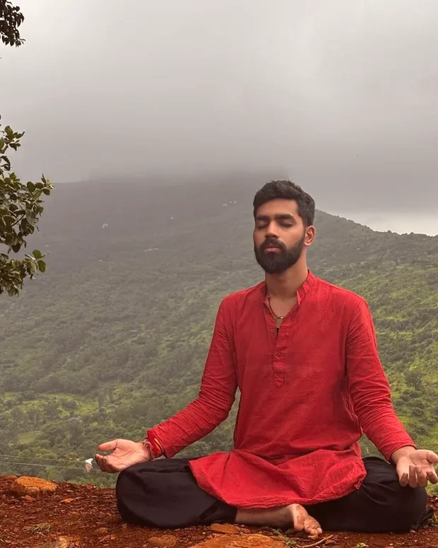 Siddhant Solanki seated in meditation above a misty valley